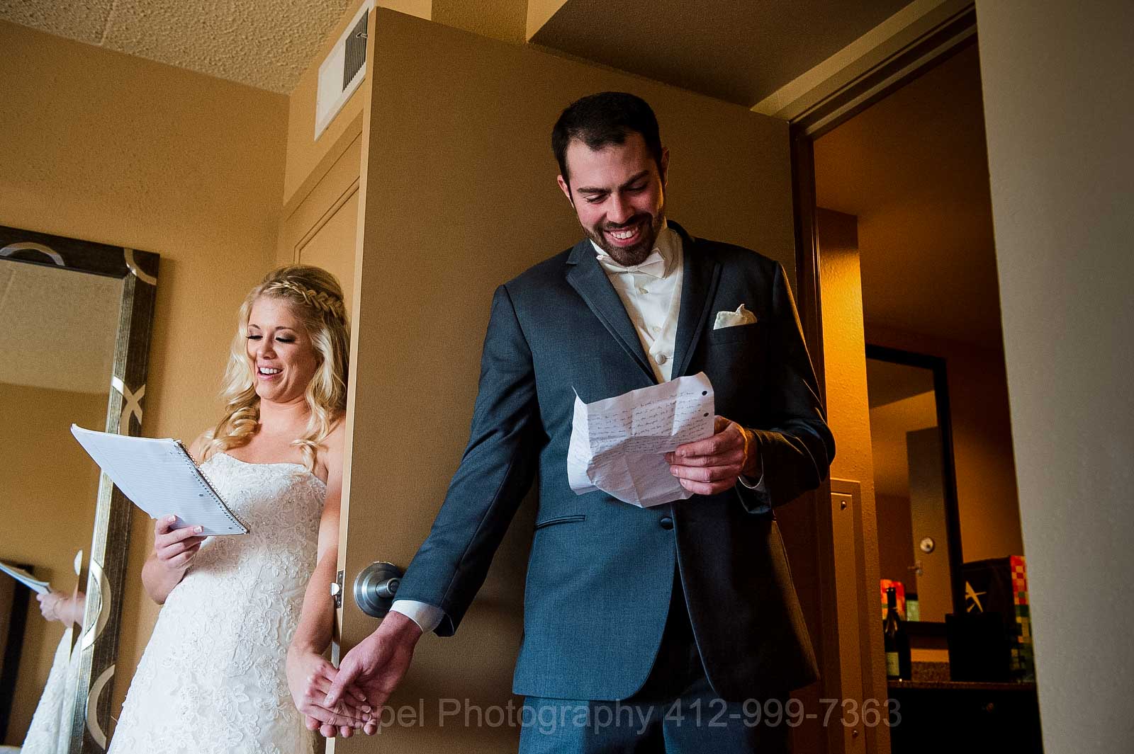 A bride and groom hold hands around a door as they read their vows to each other before their wedding at the Embassy Suites in Pittsburgh.