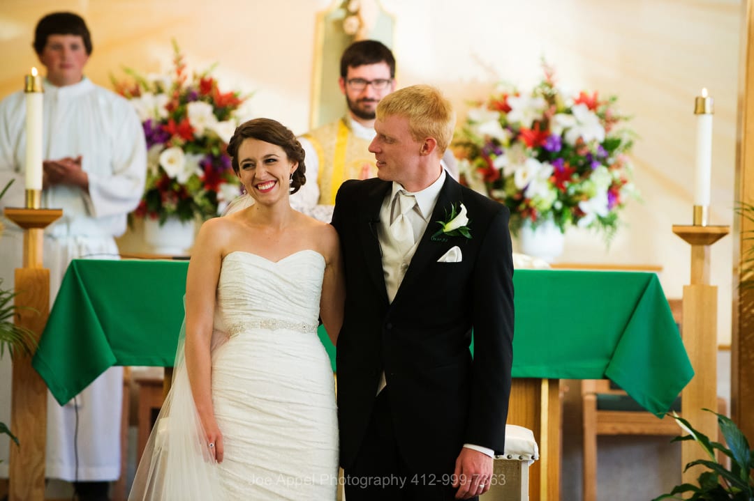 A groom looks at his bride as they are introduced at the end of their wedding ceremony at St. Columbkille.