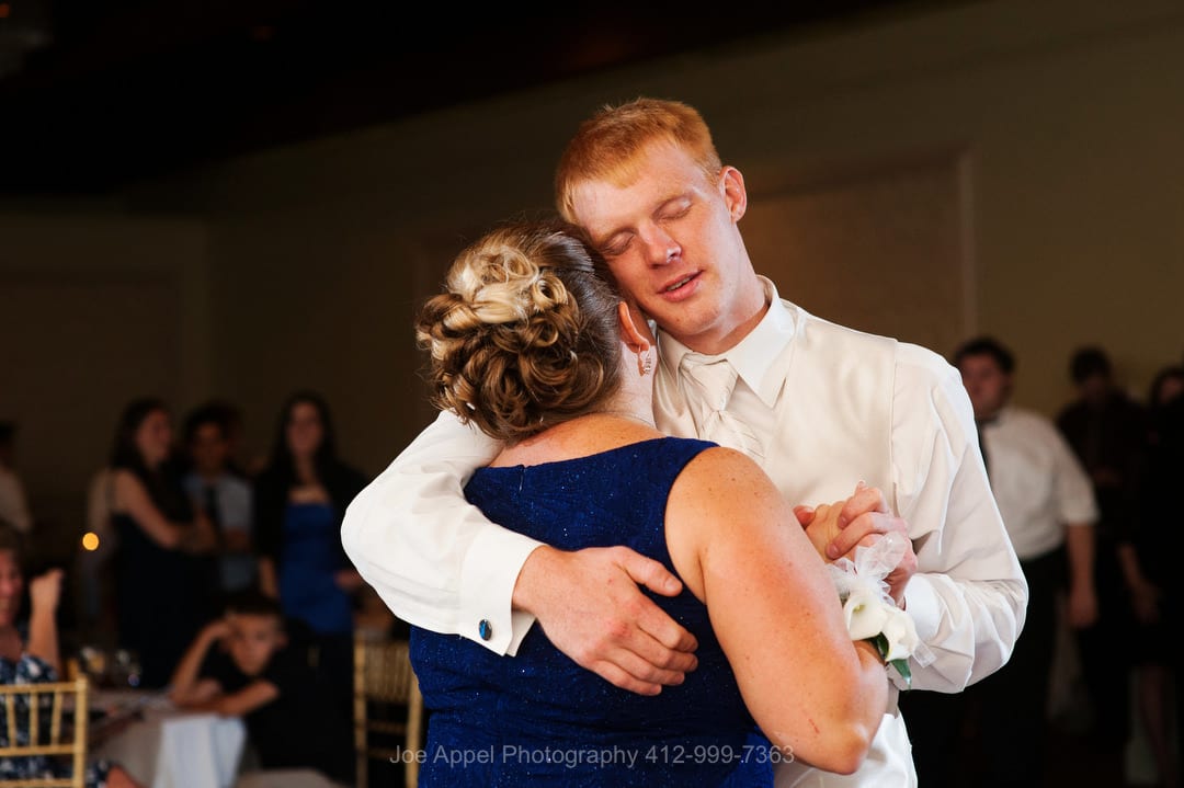 A groom closes his eyes as he rests his head against his mother's as they dance during his Montour Heights Country Club wedding.