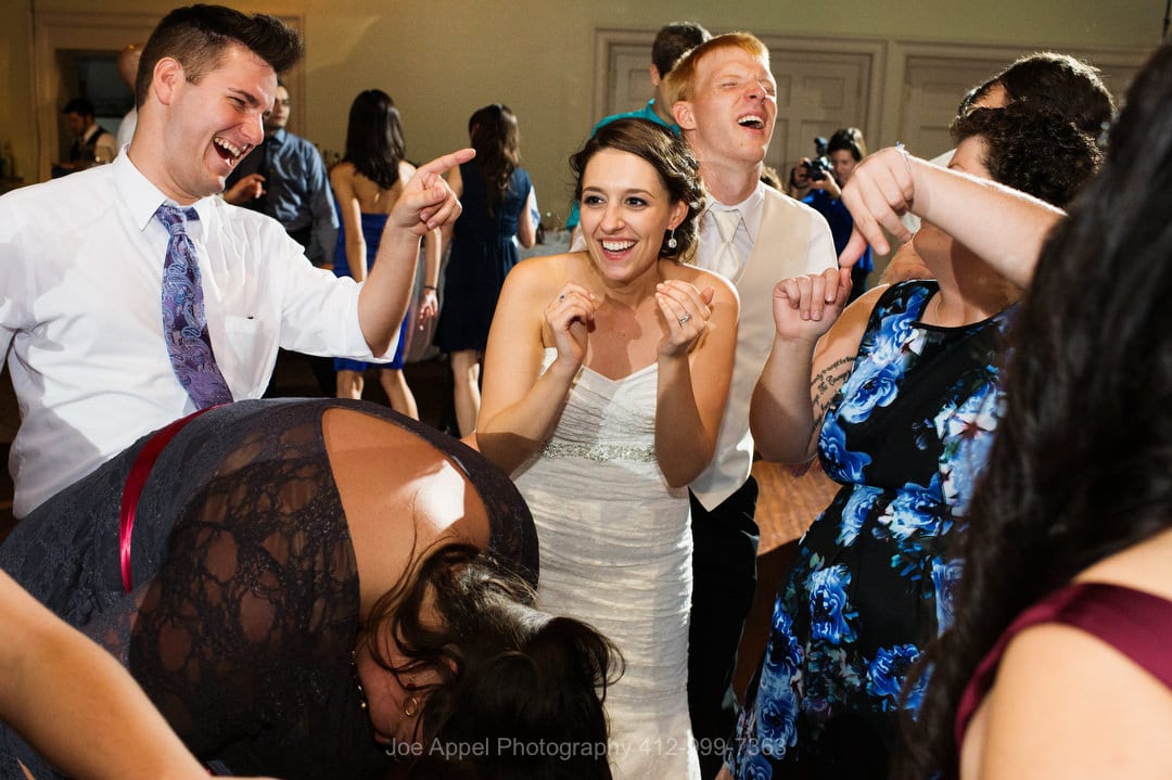 A smiling bride and groom are surrounded by their guests as they dance during their Montour Heights Country Club wedding.