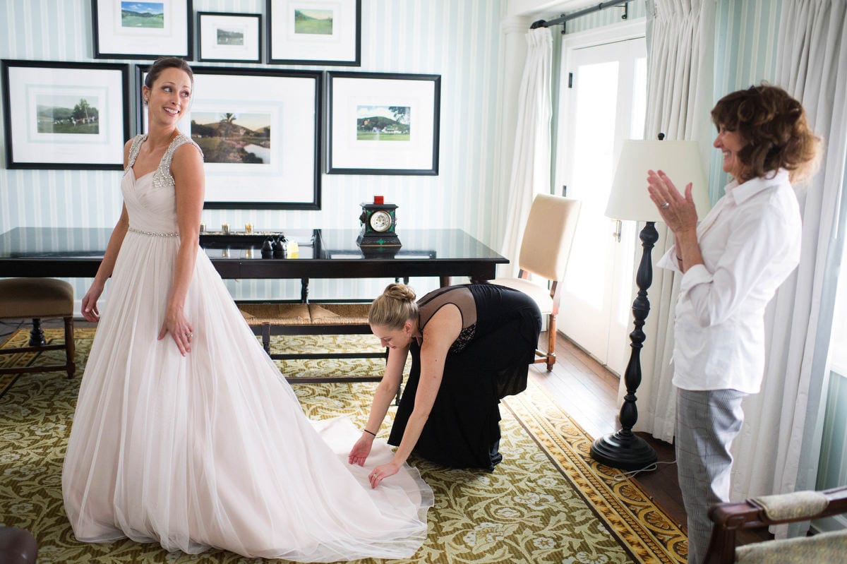 A bride has her dress smoothed by a bridesmaid as her mother looks on and applauds at the Omni Bedford Springs Resort.