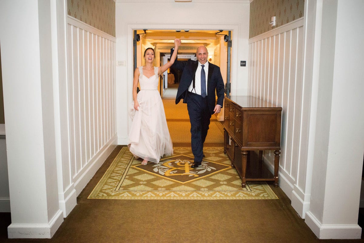 A bride and groom lift their hands into the air as they enter the Eisenhower ballroom for their wedding reception at the Omni Bedford Springs resort.
