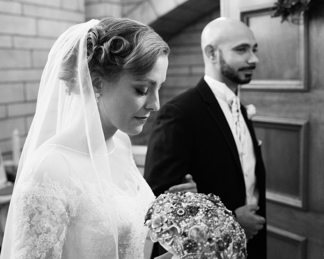 A bride looks down as she stands with her groom before their Coptic wedding at the William Penn.