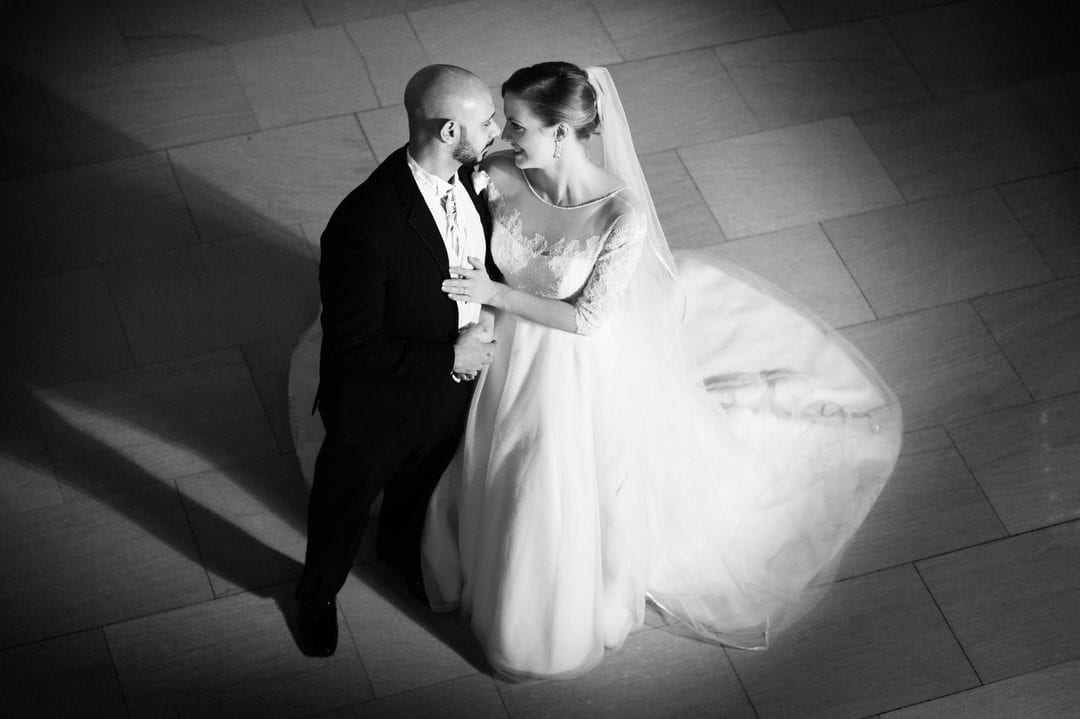 A bride and groom stand with foreheads touching as seen from above.