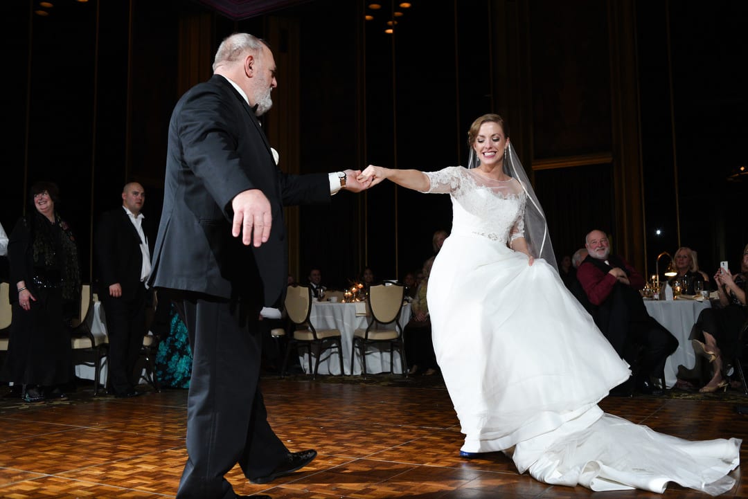 A bride holds her father's outstretched arm as they dance during her wedding in the Urban Room of the Omni William Penn in Pittsburgh.