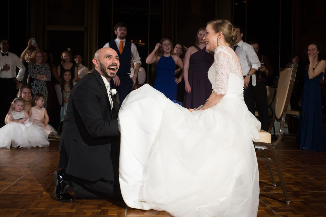 A groom laughs as he reaches under his bride's dress looking for the garter belt during a Coptic wedding at the William Penn.