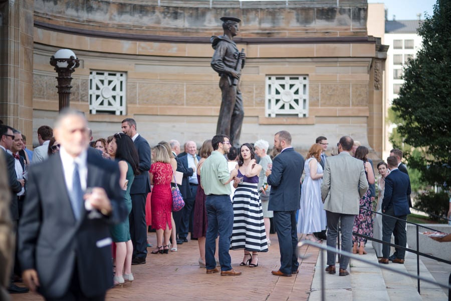 Guests at a wedding reception stand around the bronze statue of a sailor outside of Soldiers and Sailors Memorial Hall in Pittsburgh.
