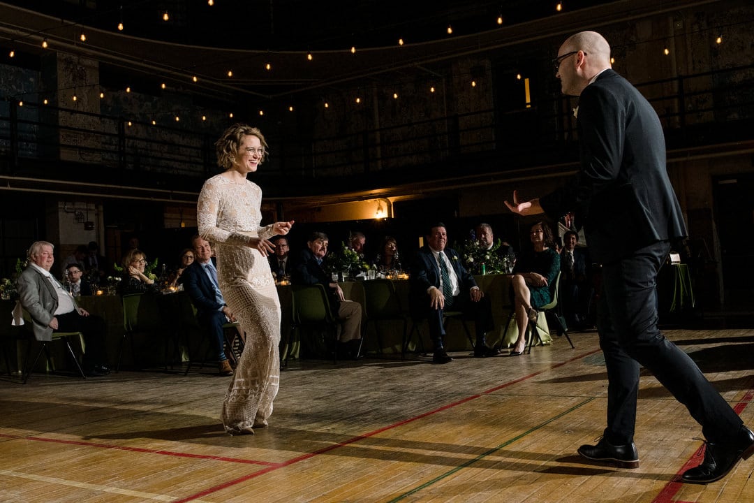 A bride and groom smile as they dance in the gym of the Ace Hotel Pittsburgh.