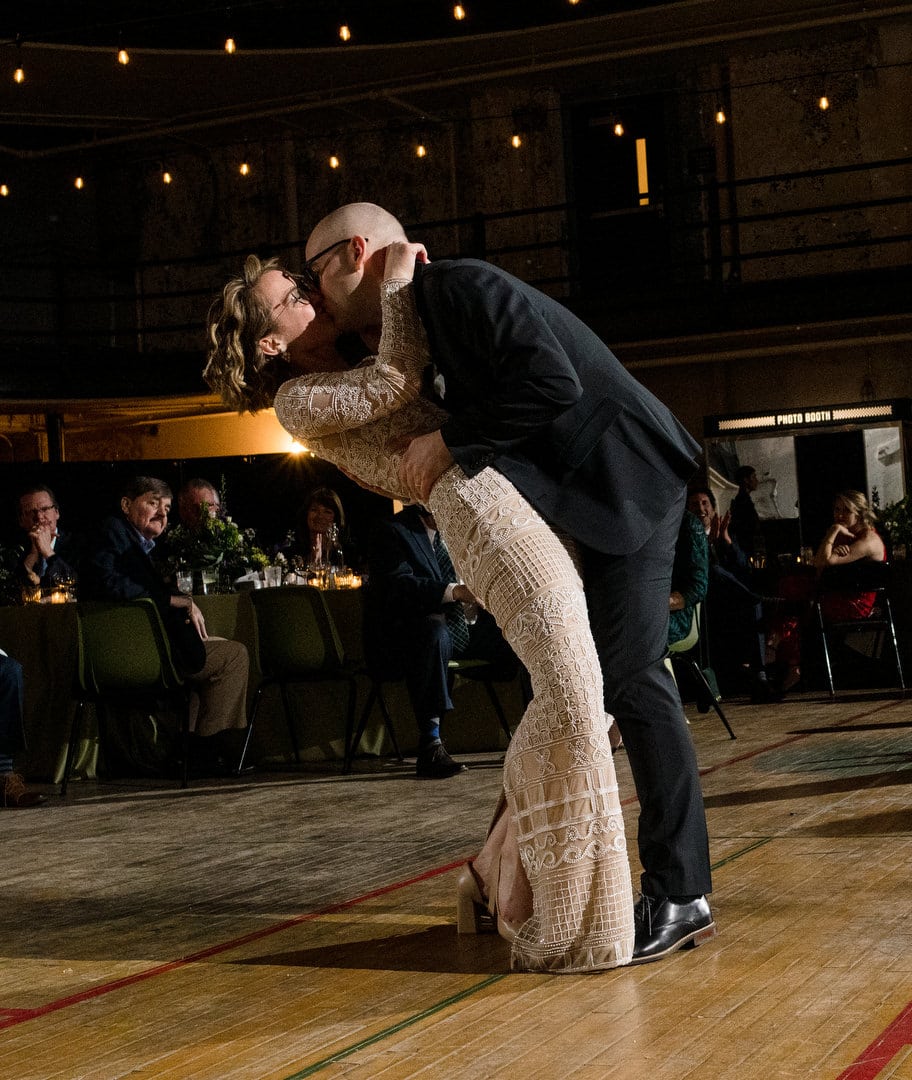 A groom dips his bride as they kiss at the end of their first dance during their Ace Hotel wedding.