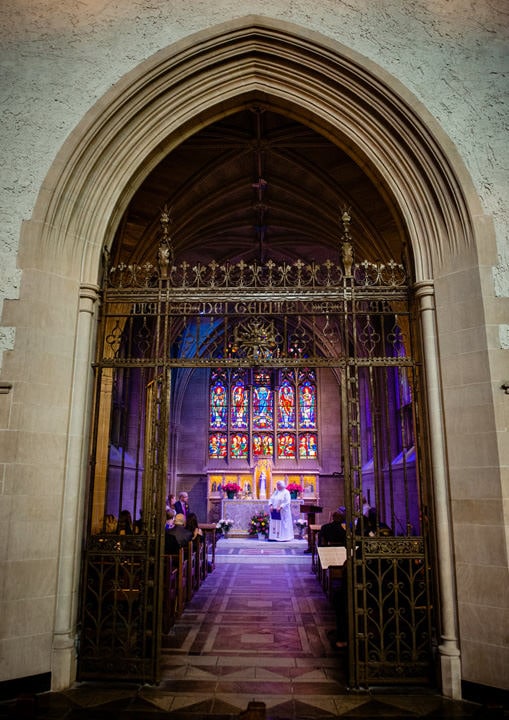 A view of a wedding ceremony through the gate of the Lady Chapel at Sacred Heart Church in Shadyside.