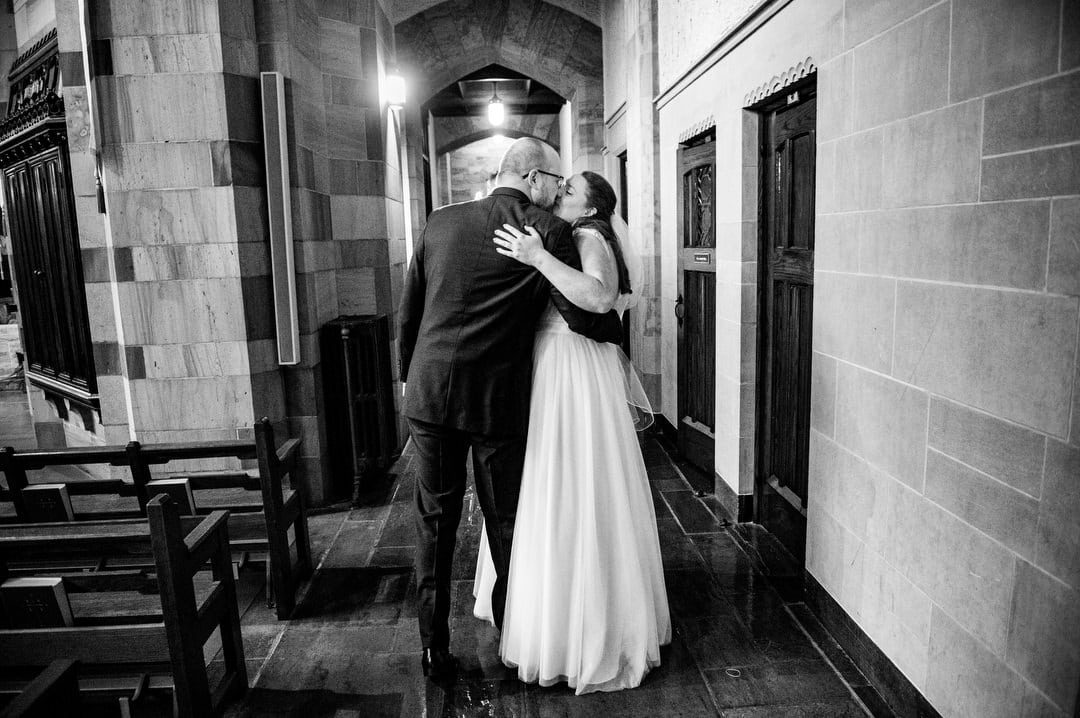 A bride and groom embrace and kiss after their wedding at Sacred Heart in Shadyside.