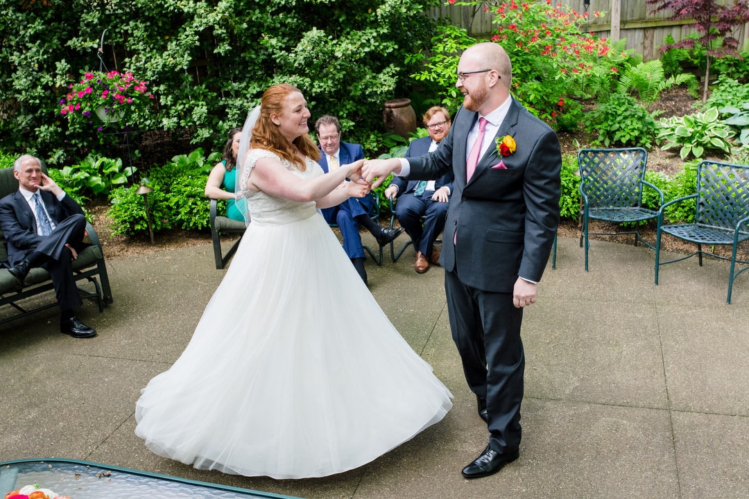 A brides' dress goes out as she spins while dancing with her groom on a patio during their wedding reception.