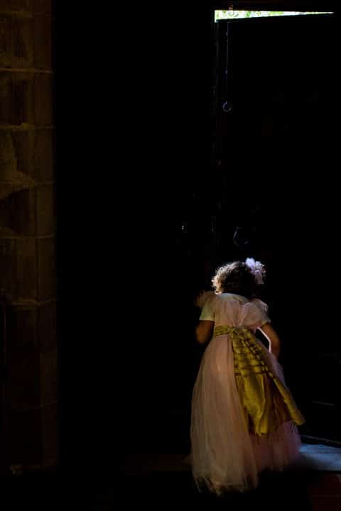 A little girl in a white dress peeks through the crack of a door at the Church of the Redeemer in Chestnut Hill, MA.