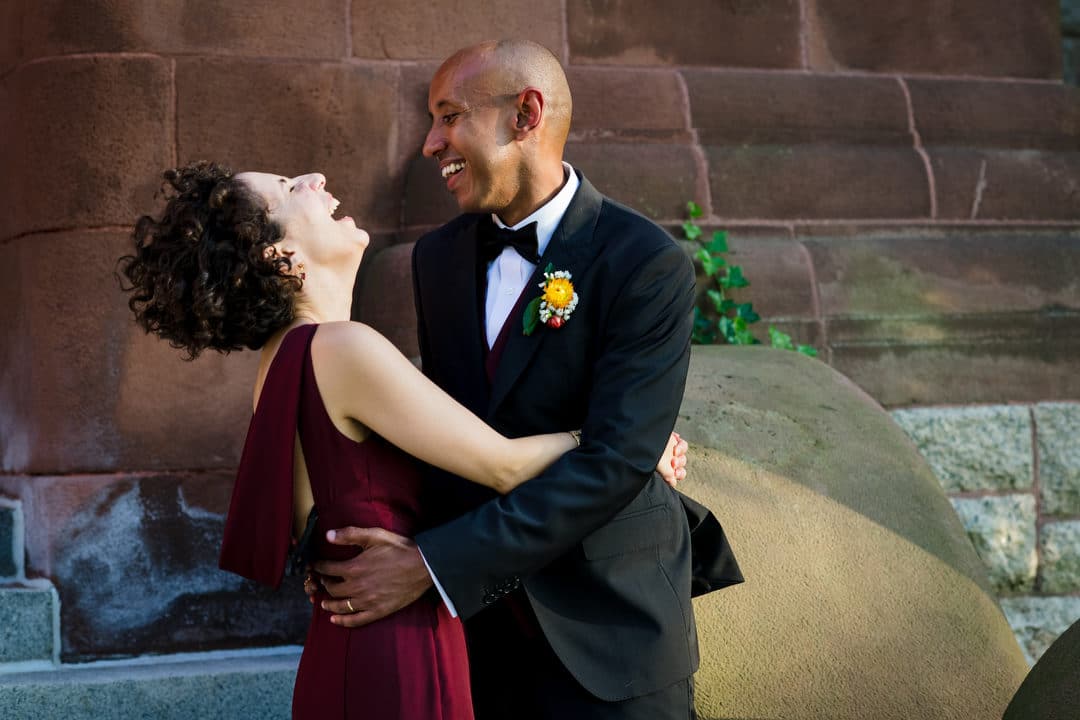 A bride and groom embrace and laugh outside of the Waterworks Museum in Cleveland Circle MA