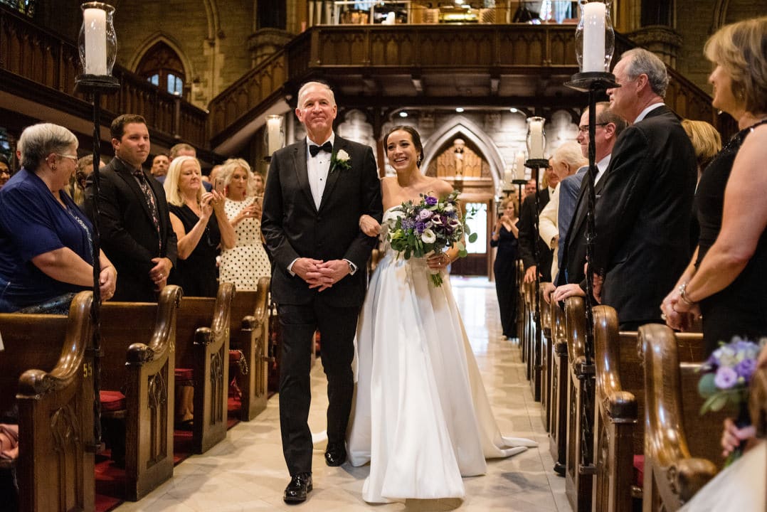 A bride and her father smile as they walk together down the aisle at First Presbyterian Church in Pittsburgh.