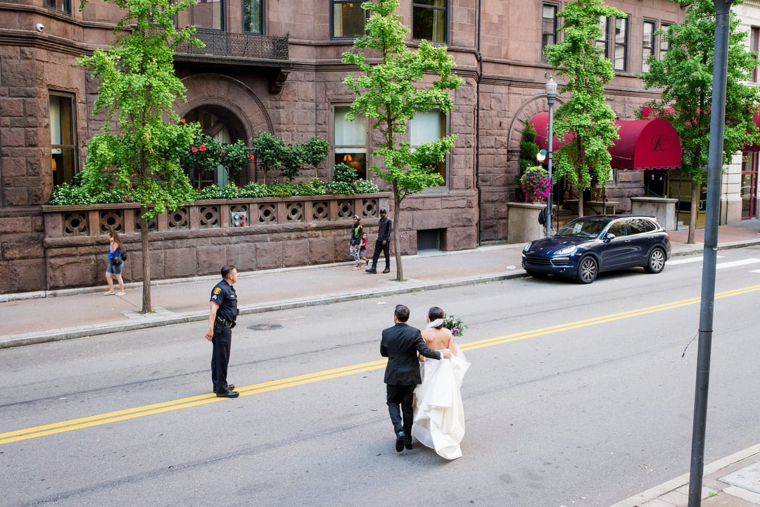 A policeman stops traffic for a bride and groom as they cross Oliver Avenue in downtown Pittsburgh to the Duquesne Club.