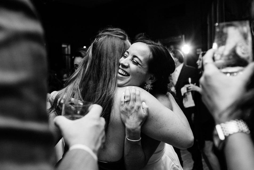 A smiling bride embraces a friend on the dance floor of her Duquesne Club wedding.