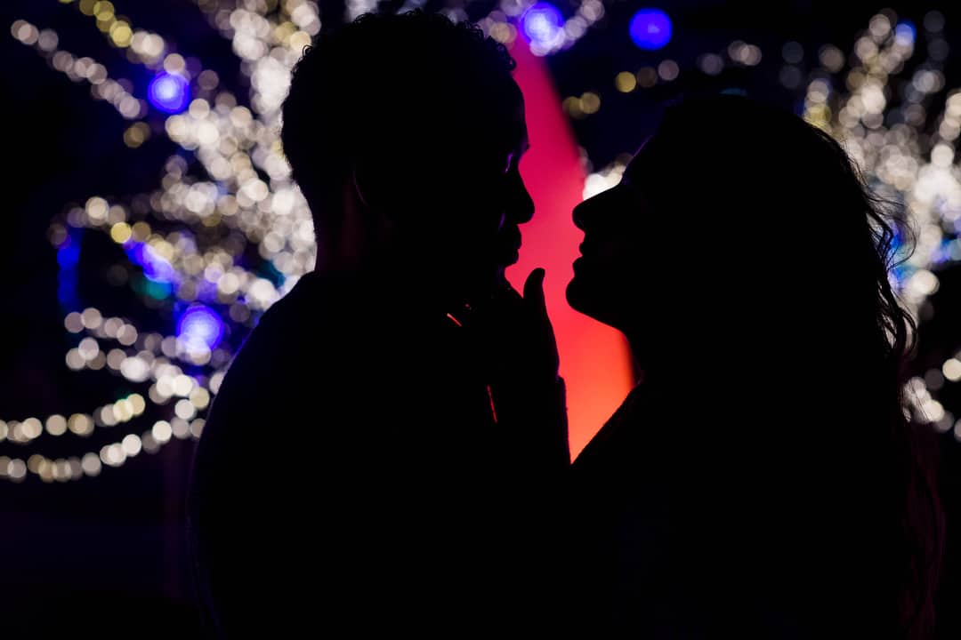 A silhouette of a young couple in front of Christmas lights at Phipps Conservatory after their marriage proposal in Pittsburgh.