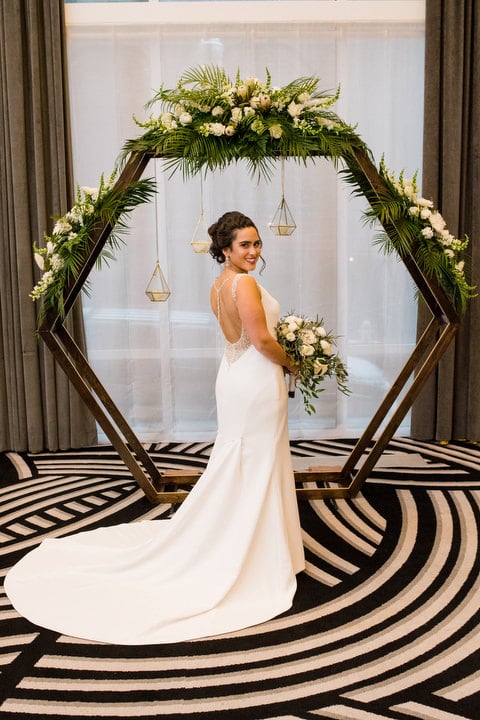 A bride smiles as she looks over her shoulder while wearing a Maggie Sottero dress at the Hotel Monaco in Pittsburgh.