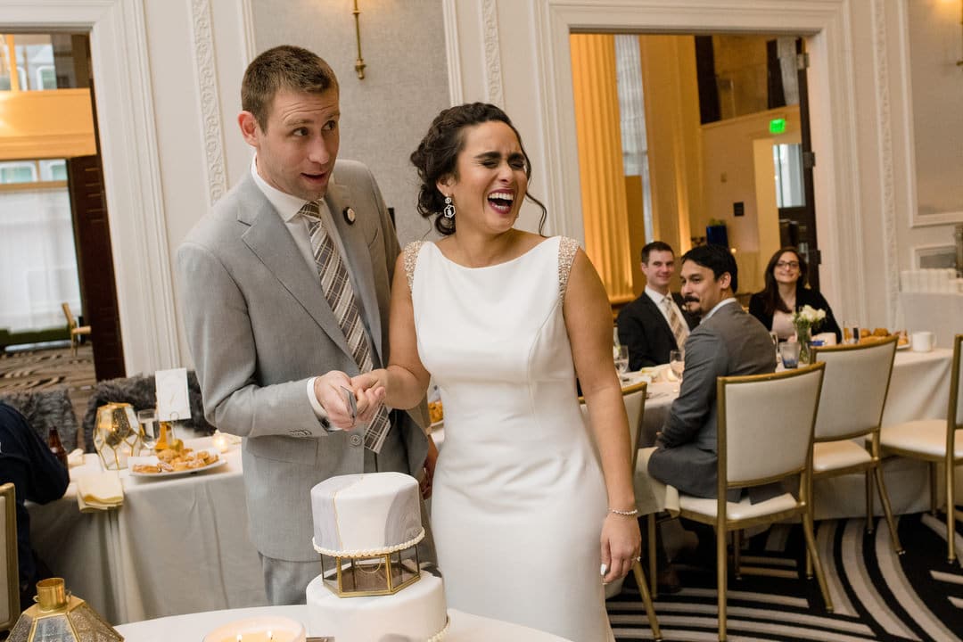 A bride laughs as she and her groom cut their wedding cake during a brunch wedding reception at the Hotel Monaco in Pittsburgh.