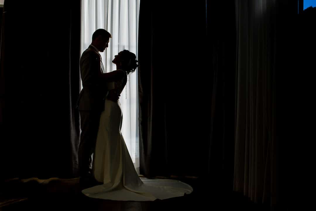 A silhouette of a bride and groom in front of a window at the Hotel Monaco in Pittsburgh.