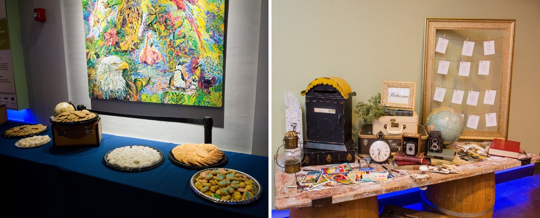 A cookie table beneath a painting of birds and an escort table with old cameras, clocks, a globe and postcards during a Pittsburgh Aviary wedding.