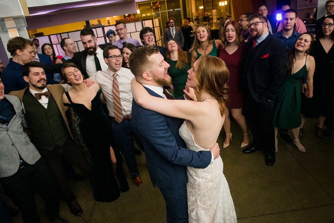 A bride and groom dance as their guests circle them and sing at their Pittsburgh Aviary wedding.