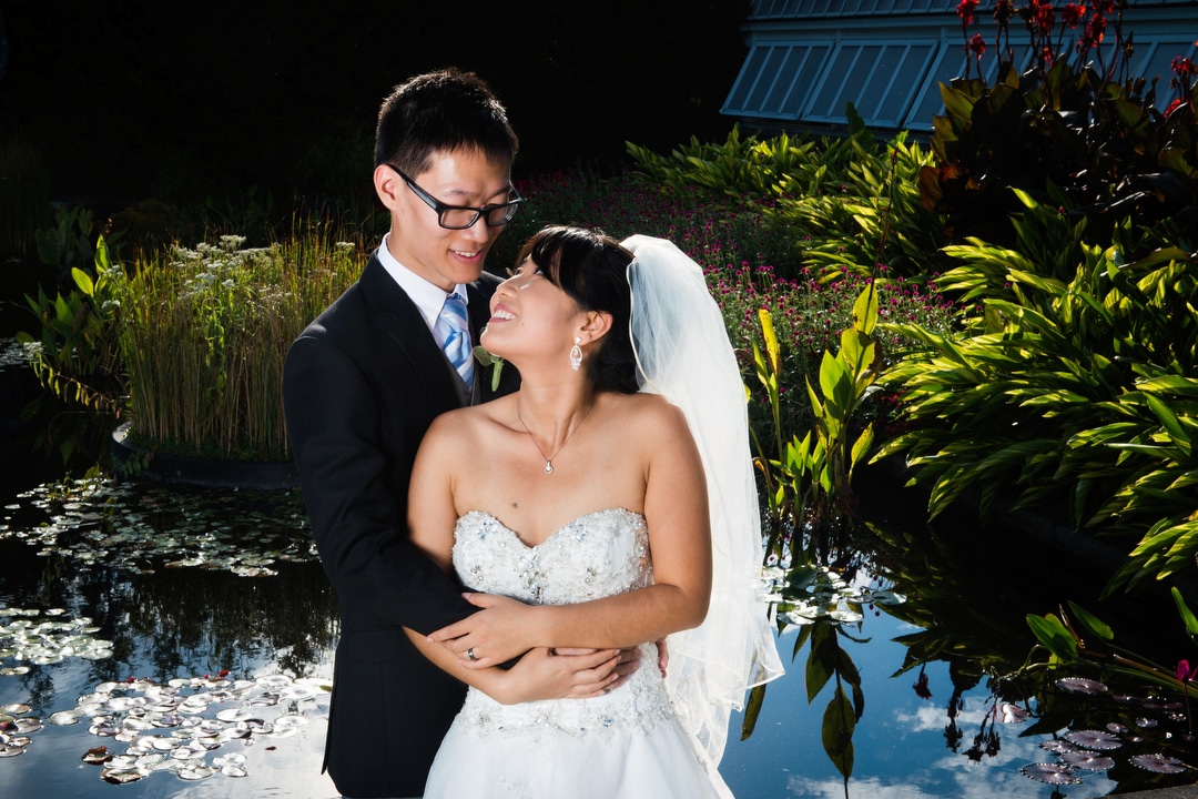 A couple embraces during a portrait next to an outdoor lily pond at Phipps Conservatory and Botanical Gardens.