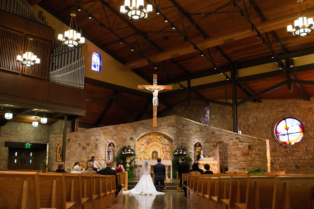 A bride and groom kneel at the altar during their small and intimate wedding ceremony at St. Louise de Marillac in Bethel Park.