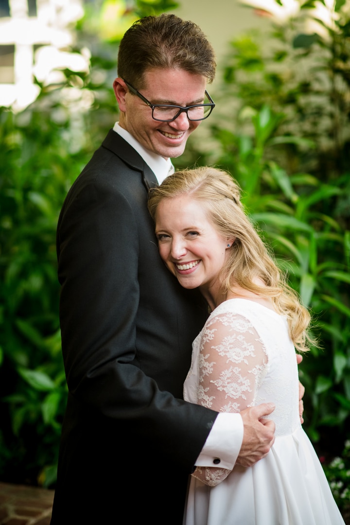 A bride smiles as she leans against her groom after their small wedding at Phipps.