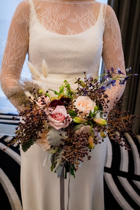 A bride holds her pink, purple and green bouquet.