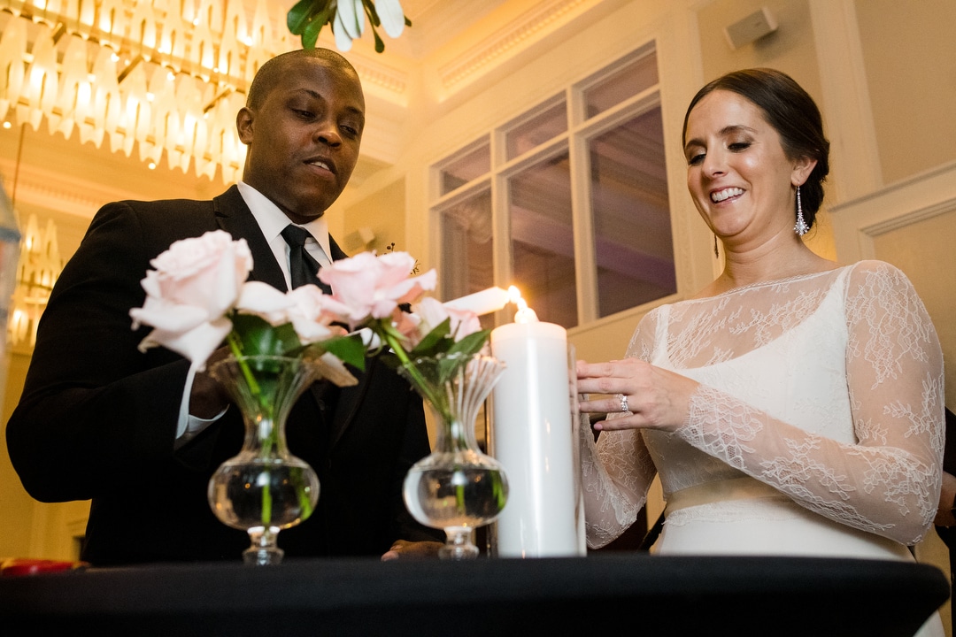 A bride and groom light a unity candle.