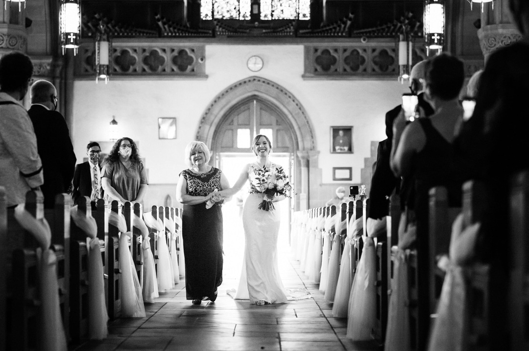 A bride and her mother hold hands as they walk down the aisle at St. Bernard's Church in Mt. Lebanon.