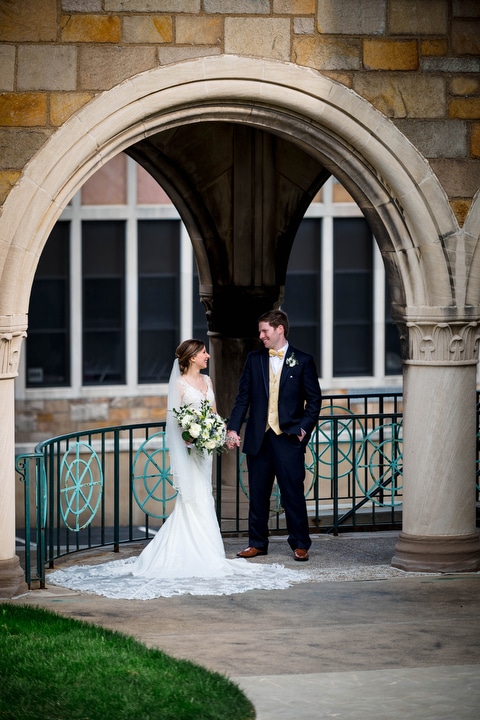 A bride and groom stand beneath a stone arch at St. Bernard Church.