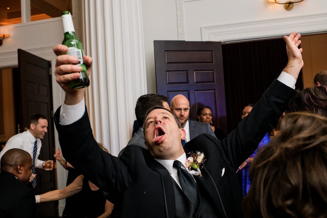 A man holds a bottle of beer up while he dances during a wedding reception at the Hotel Monaco in Pittsburgh.