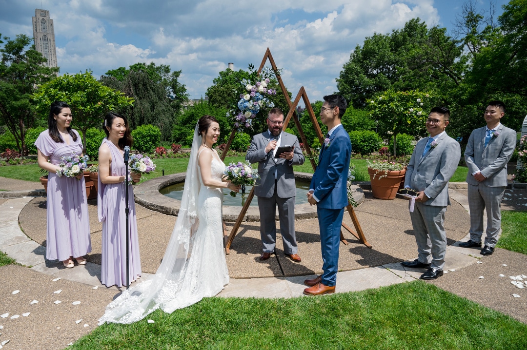 A collection of triangles forms the backdrop as a couple exchange wedding vows during their phipps outdoor wedding.