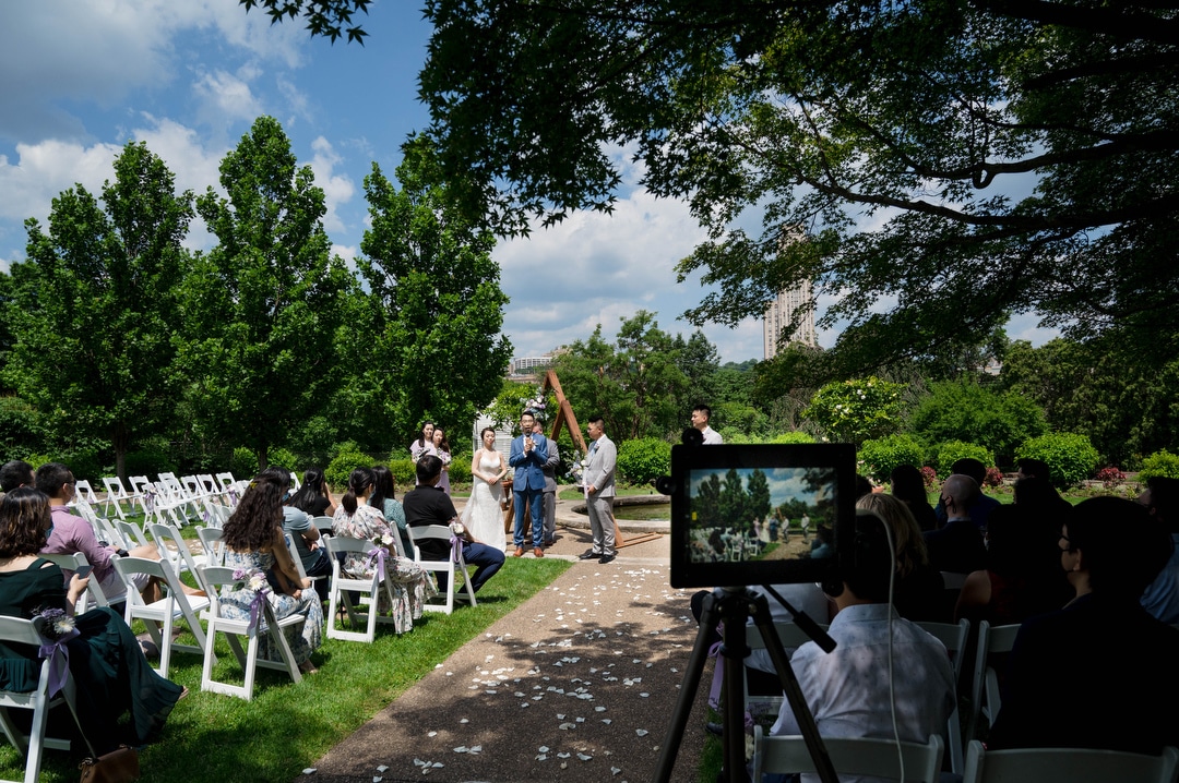 The screen of an iPad shows the scene from a Phipps outdoor wedding that as it is livestreamed.