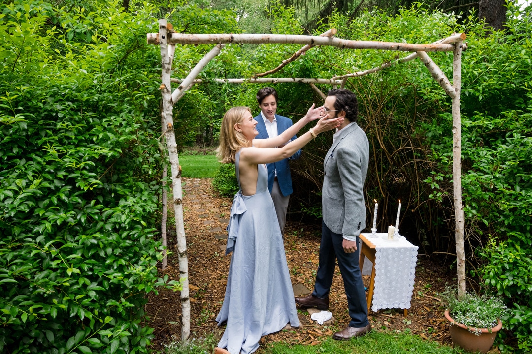 A bride reaches to kiss her groom at the end of their intimate backyard wedding.