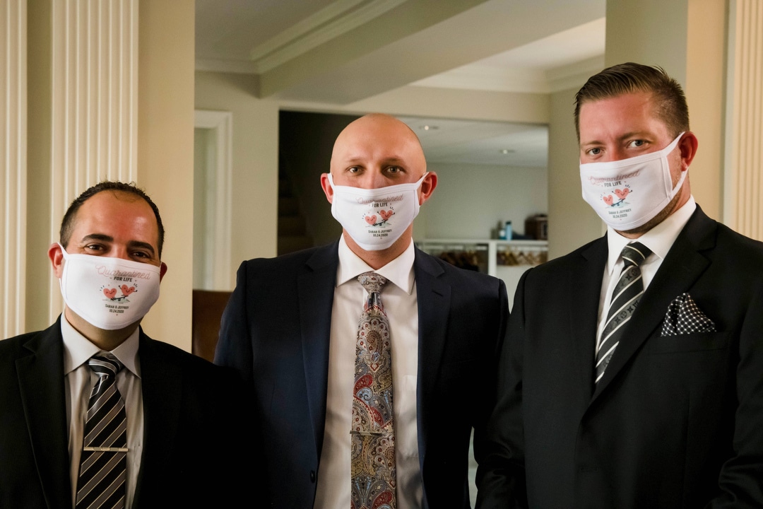 Three groomsmen wear masks personalized with the bride and groom's names.