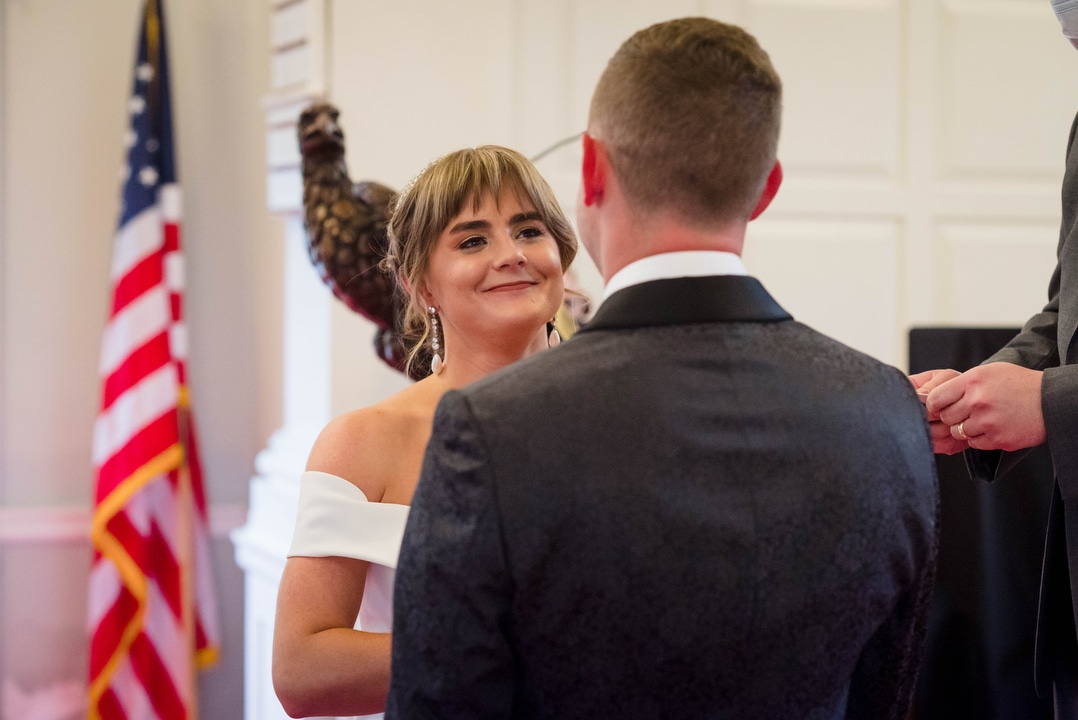 A bride smiles as she exchanges vows with her groom.