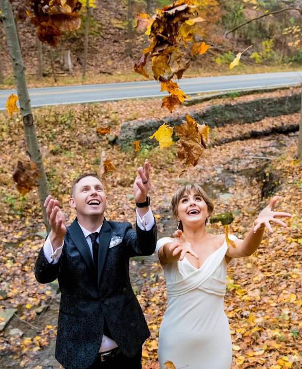 A bride and groom throw leaves into the air.