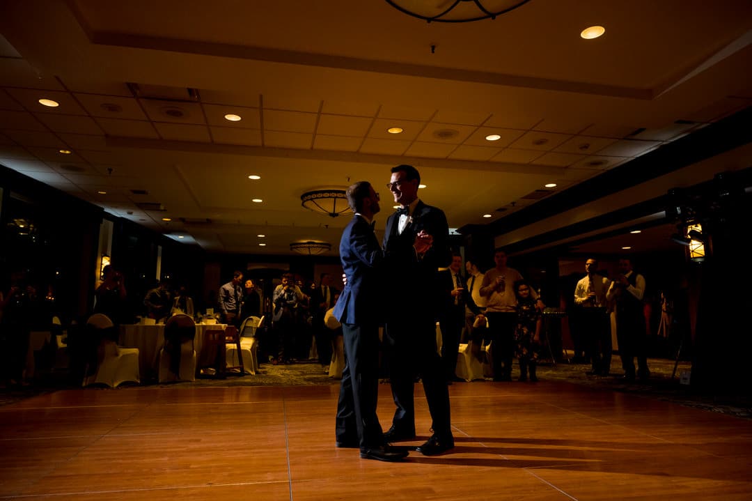 dark, moody photo of two grooms sharing their first dance at the Sheraton Station Square in Pittsburgh.
