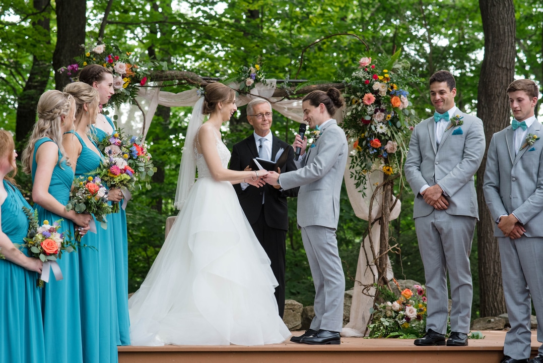 A bride and groom hold hands as they are surrounded by their bridal party during their summer wedding at seven springs
