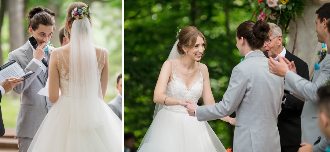 A groom wipes a tear while his bride smiles during a summer wedding at seven springs
