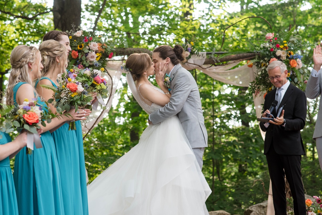 a bride and groom kiss at the end of the ceremony during their summer wedding at seven springs