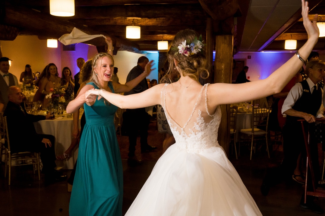 A bride dances with a bridesmaid during her summer wedding at seven springs.