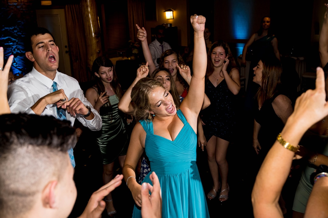 A bridesmaid in a blue dress raises her fist as she dances