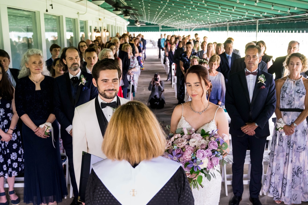 Overview of a wedding ceremony at Oakmont Country Club with the bride and groom standing front and center.