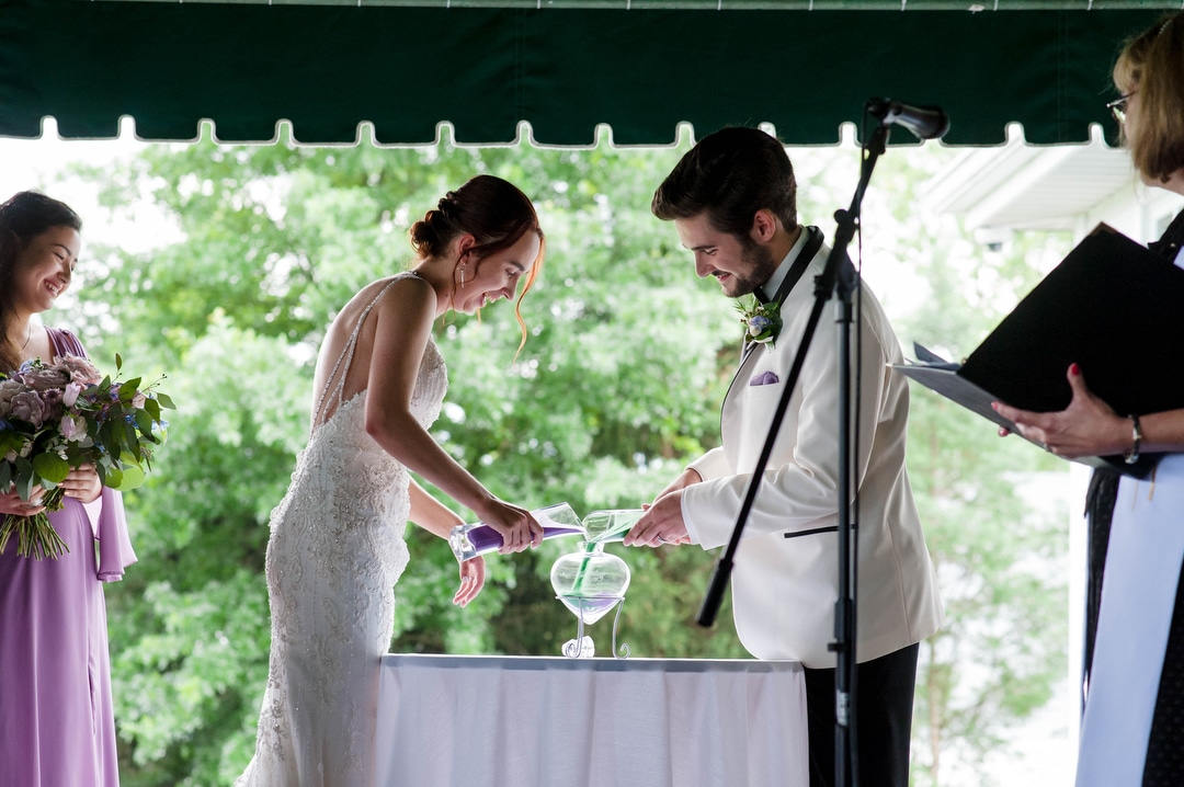 A couple pours sand into a heart-shaped vessel during their wedding at Oakmont.