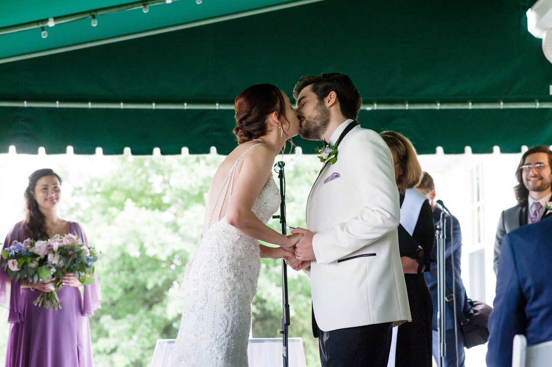 A couple kisses at the end of their wedding at Oakmont Country Club.